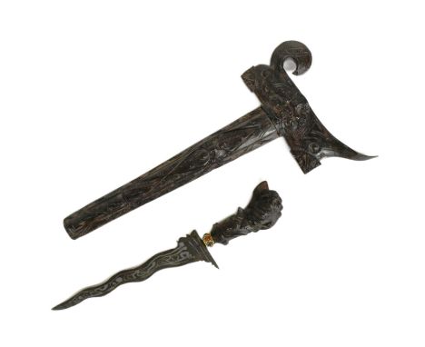 An early 20th Century Indonesian Kris / Keris dagger with an intricately carved hilt and scabbard, gilt metal collar with red