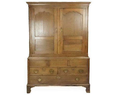 A George III oak press cupboard. In two parts, the upper part with two arched moulded doors, the lower part fitted three dumm