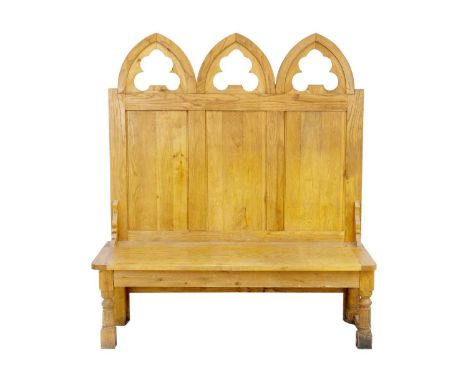 An oak Gothic style hall bench. 20th century, the tall panel back with lancet tops, above a solid seat on turned square secti