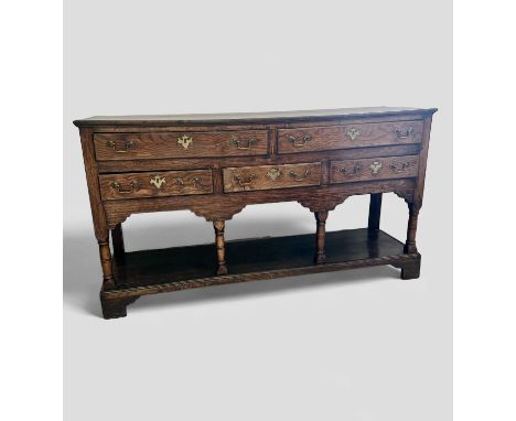 A George III low dresser The drawers with elm fronts above four turned columns, a low shelf and bracket feet. 149x42.5cm and 