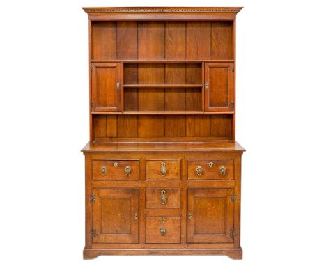 A George III style oak dresser. The upper section with open shelves and twin cupboards over and arrangement of five drawers a