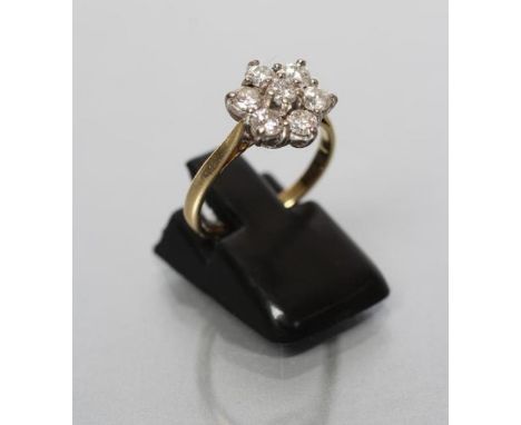 A SEVEN STONE DIAMOND CLUSTER RING, the round brilliant cut stones claw set to plain shoulders and 18ct gold shank, Birmingha