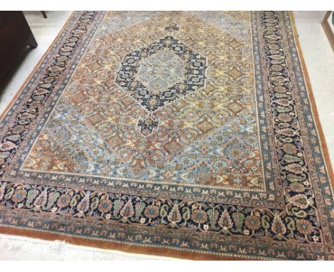 A PERSIAN STYLE CARPET, modern, the caramel floral field with navy and pale blue central gul, pale blue spandrels, within a n