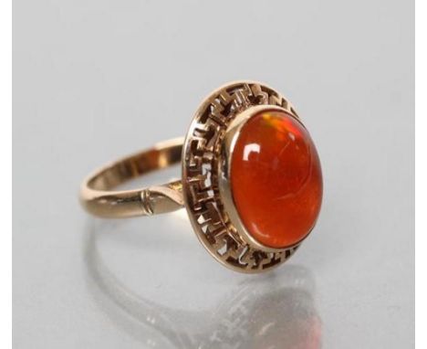 A COCKTAIL RING, the oval cabochon polished fire opal collet set to an open key border and a plain shank, stamped 14k, size M