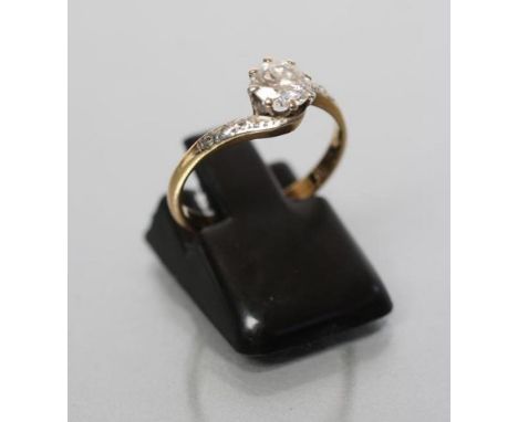 A SOLITAIRE DIAMOND RING, the round brilliant cut stone of approximately 0.6cts claw set to scroll shoulders each set with a 