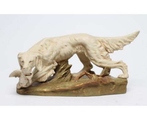 A ROYAL DUX BISQUE PORCELAIN SETTER, early 20th century, modelled holding a game bird in its mouth on a naturalistically moul