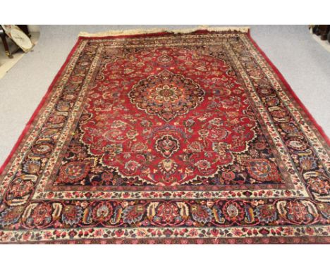 A PERSIAN CARPET, 20th century, the red field with central floral gul in navy blue, green and ivory within a scrolling foliat