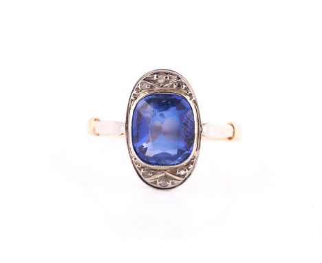 A synthetic sapphire and diamond ring,the oval plaque collet-set with a cushion-shaped synthetic sapphire, within a rose-cut 