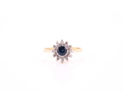 A sapphire and diamond cluster ring, the round mixed cut sapphire, surrounded with twelve brilliant cut diamonds, the yellow 