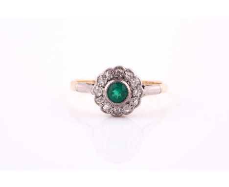 An emerald and diamond cluster ring; the central circular cut emerald in a millegrain mount within a border of twelve old cut