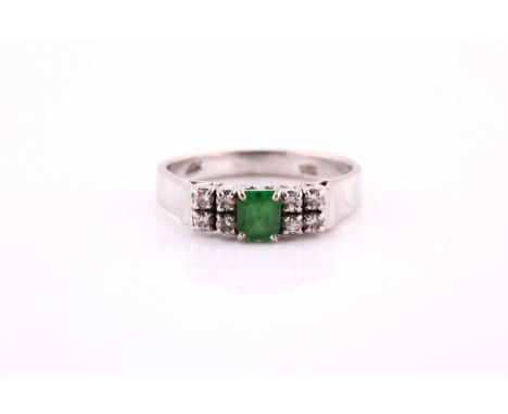 An emerald and diamond seven stone half hoop ring; the emerald cut emerald claw set between four stone round brilliant cut di