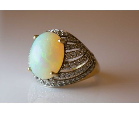 An opal and dress ring, the 14 x 10mm opal claw set to a bombé pierced paste set mount, to yellow precious metal mount, stamp