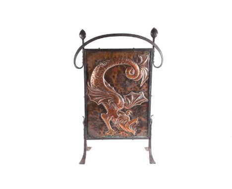 An Arts &amp; Crafts style fire screen, with a hammered copper panel depicting a dragon, in an iron frame on four splayed fee