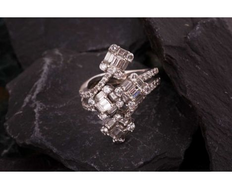 A diamond dress ringOf bifurcated design, obliquely-set to the front with four clusters of baguette and brilliant-cut diamond