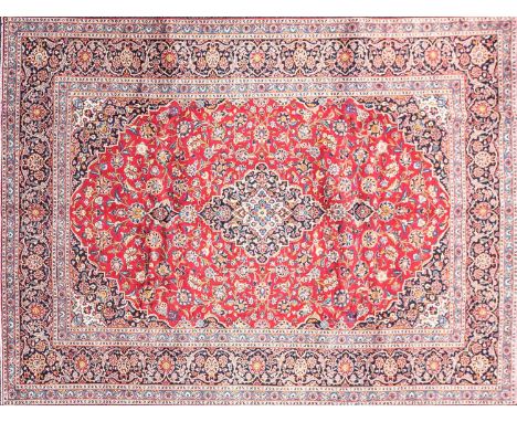 A 20th-century red ground Kashan carpet, with a central medallion within meandering borders. 346 cm x 270 cmCondition report: