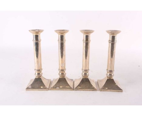 A set of four sterling silver table candlesticks with simple girdled bodies and concave square loaded bases. Each marked Stir