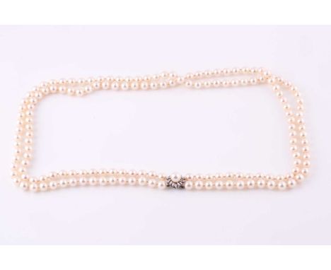 A two row cultured pearl necklace, the light cream pearls with pink overtones, 7-7.5mm diameter, the clasp centred by an 8mm 