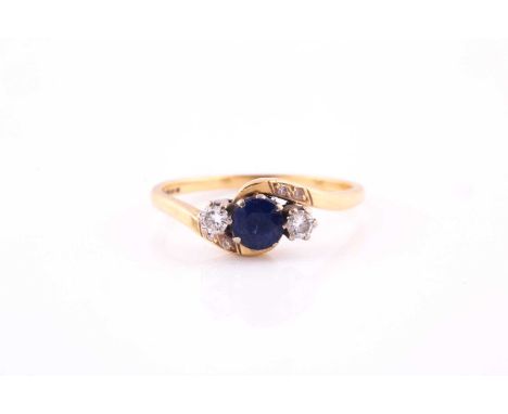 A sapphire and diamond three stone cross over ring, the round mixed cut sapphire flanked by two brilliant cut diamonds, the 1