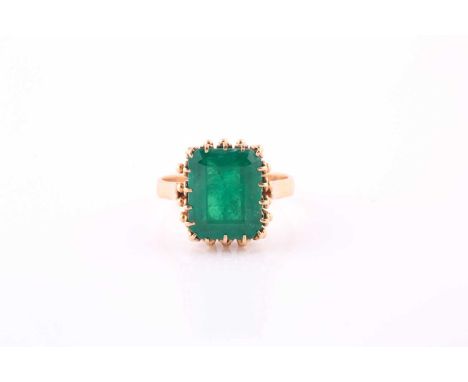 Emerald single stone ring, the rectangular step cut stone claw set to a yellow precious metal mount with ornate gallery, emer