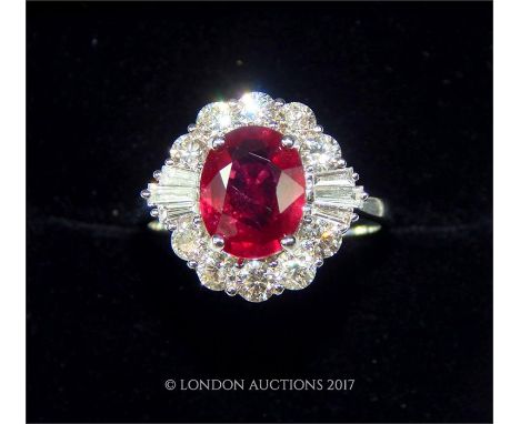 A boxed 18 ct white gold ruby and diamond cluster ring, the central faceted oval ruby is claw-set and framed by a coronet clu