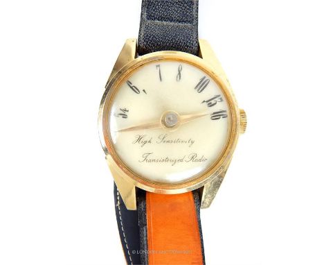 A vintage, novelty, high sensitivity transistor radio in the form of an oversized gilt metal wrist watch on a large brown and