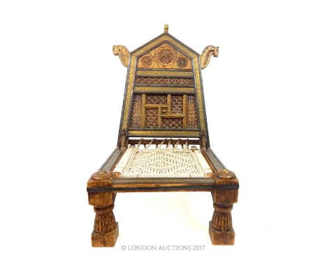 A first half of the 20th century Persian carved teak low chair, set with brass, with carved panels and a woven seat, 77 x 51 