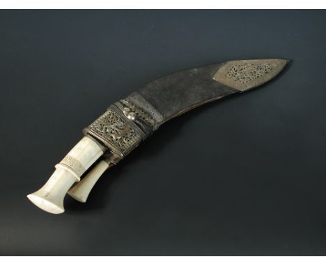 A late 19th century Kukri, the large blade and two small blades with ivory handles, the leather scabbard with pierced white m