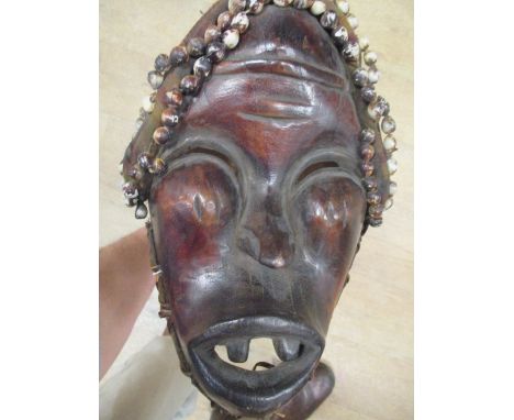 A hardwood dance mask, Dan people, Liberia, mounted with plant fibre, fabric and cowrie shells, 46cm (18in) wide  