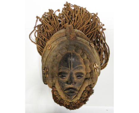 A carved wood dance mask, Dan people, Liberia, applied with woven plant fibre and braided cord hair and applied with cowrie s