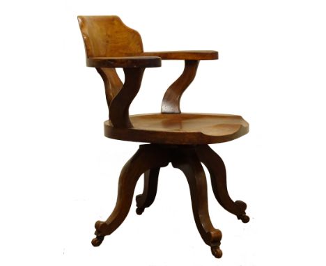 Edwardian walnut swivel office chair, curved shaped back and arms with saddle seat the four scrolled supports with ceramic ca