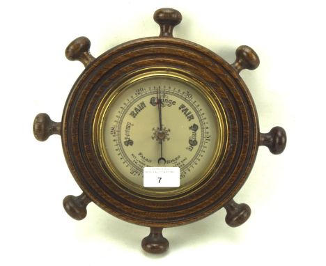 A 20th century barometer mounted in brass and oak in the shape of a ship's wheel, total diameter circa 27.5cm
