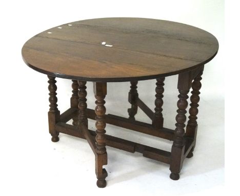 An oak gateleg oval table with bobbin turned supports, on bun feet, 70cm x 125cm x 104cm