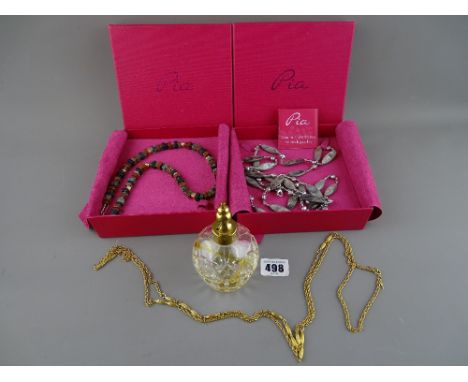 Two modern boxed necklaces by Pia, a gold coloured vintage necklace and a brass topped glass perfume bottle in a Stuart Cryst