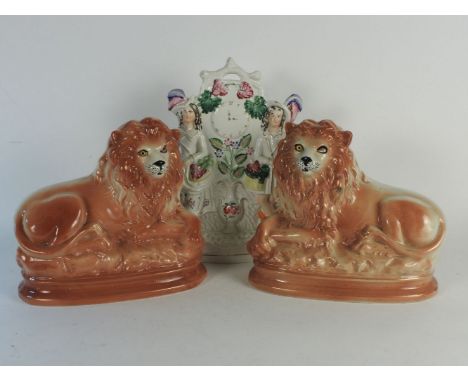 A pair of 19th Century Staffordshire lions, together with a Staffordshire flatback figure group of two figures in highland dr