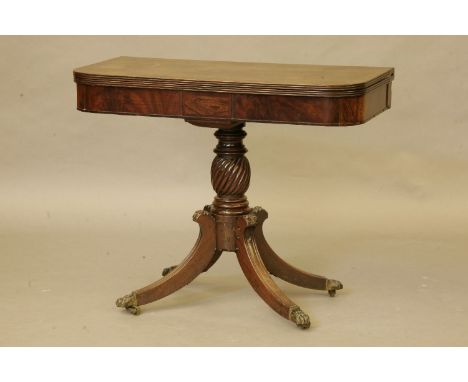 A Regency mahogany fold over card table, the shaped top with a reeded edge over a plain frieze, over a wrythen baluster colum