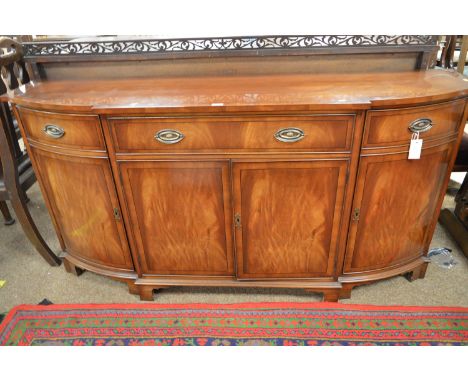 A Regency style mahogany and yew banded sideboard, the shaped top above three frieze drawers, a pair of central cupboards fla