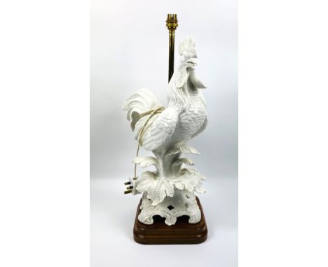 A large white glazed ceramic table lamp in the form of a cockerel standing upon a naturalistic base, mounted upon a hardwood 