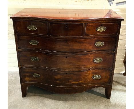 A late 18th century Georgian inlaid mahogany serpentine chest of three short over three long drawers, with oval brass handles
