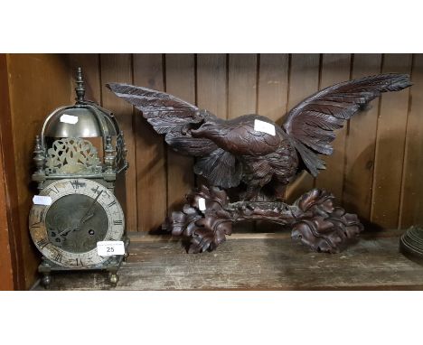 A brass lantern clock and a wooden carved eagle 