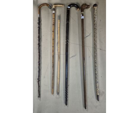 A bundle of six walking sticks including snakeskin, military swagger stick, carved wood, dog's head handle, etc.Condition:- G