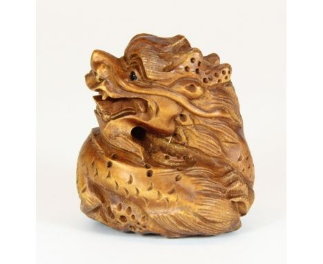 A carved wooden netsuke of a dragon resting on a lotus leaf H 4cm