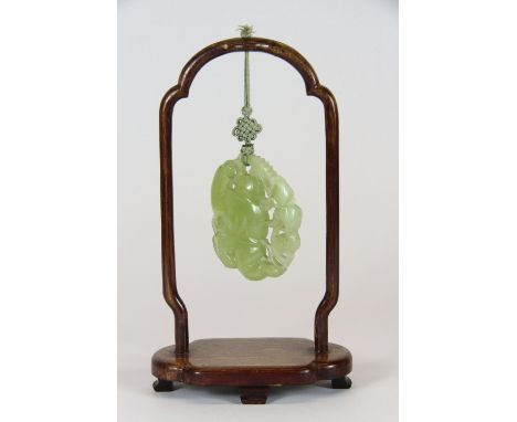A Chinese carved jade amulet (5.5cm x 4.8cm) on wooden stand