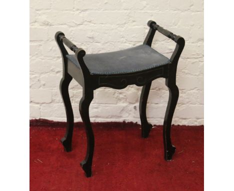 A Victorian ebonized piano stool with under seat storage and raised on cabriole supports.