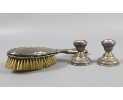 A silver backed brush and a pair of silver dwarf candlestick assayed Birmingham.