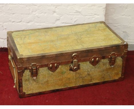 A metal bound travel trunk decorated with maps of England.