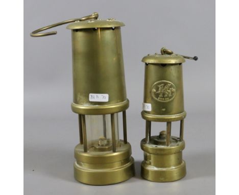 A brass cased miners lamp along with a smaller brass miners lamp.