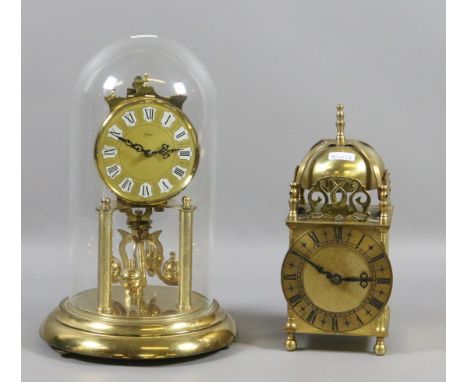 A brass anniversary clock under glass dome along with a brass lantern clock.