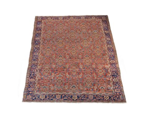 A Heriz carpet, the madder field decorated with stylised foliate motifs within an overall design, within a blue border, appro