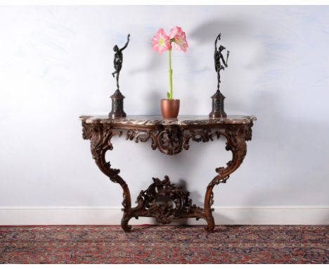 A Louis XV carved oak console table, circa 1735, the serpentine shaped marble top with moulded edge, above a pierced, C-scrol