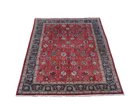 A Tabriz carpet, the red field decorated with an overall design of meandering floral branches, within a dark border decorated